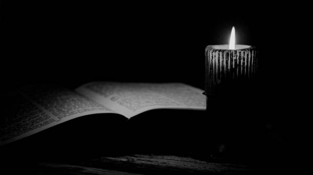 istock Open Bible And Burning Candle In Black And White Display. 1329005079