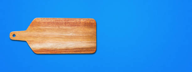 istock Wooden cutting board isolated on blue. Horizontal banner 1329005375
