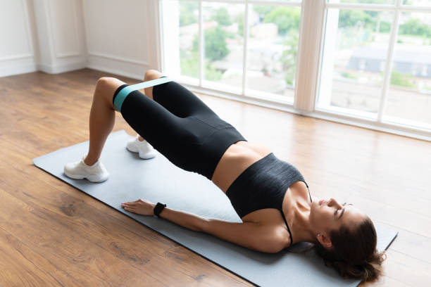 mujer en ropa deportiva negra haciendo ejercicio con banda elástica - correa objeto fabricado fotografías e imágenes de stock