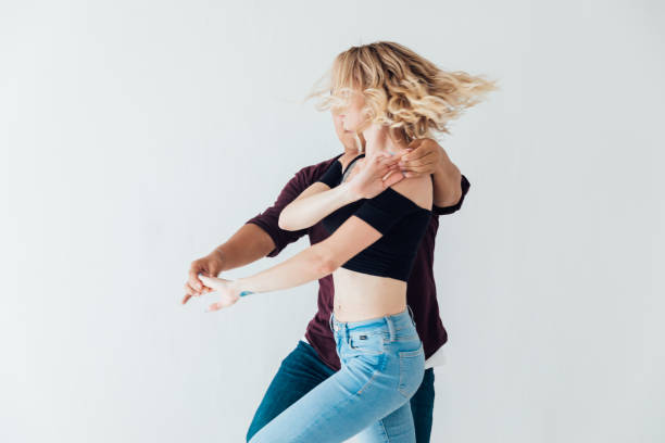 a man and a woman dance bachata music in a white room a man and a woman dance bachata together to music in a white room female salsa dancer stock pictures, royalty-free photos & images