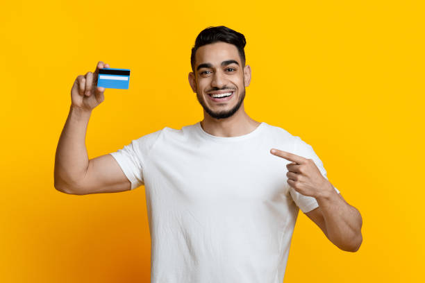 istock Positive arab guy recommending credit card, yellow background 1329006663