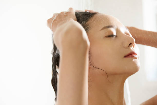 eine junge asiatin, die im badezimmer shampoonieren - bathtub asian ethnicity women female stock-fotos und bilder