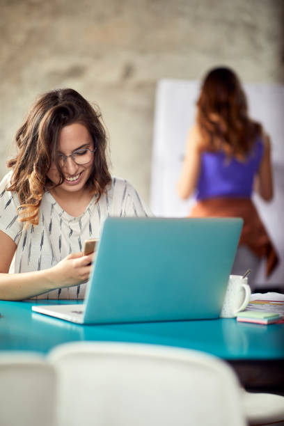 Young woman is texting on smartphone while working in the office