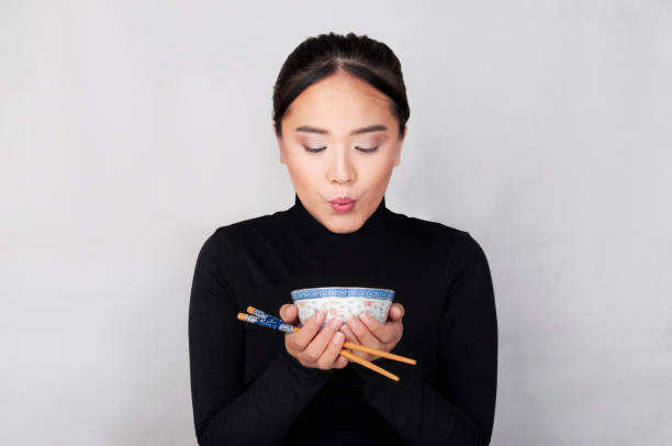 oriental girl dressed in black blows the food inside her chinese bowl with stick in your hands - dining nautical vessel recreational boat europe imagens e fotografias de stock