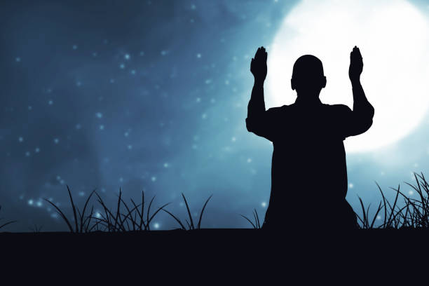 istock Silhouette of Muslim man sitting while raised hands and praying 1329012808