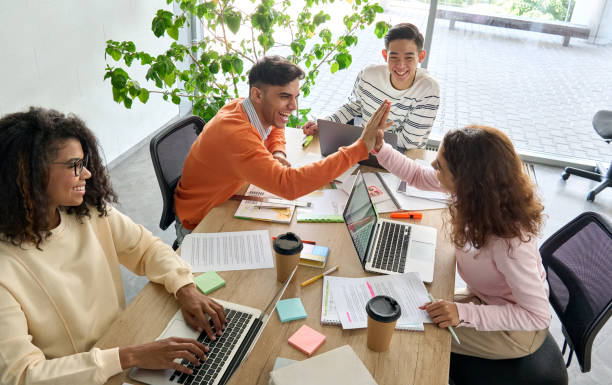 istock Four cheerful coworkers creative team working together in office using laptop. 1329013239