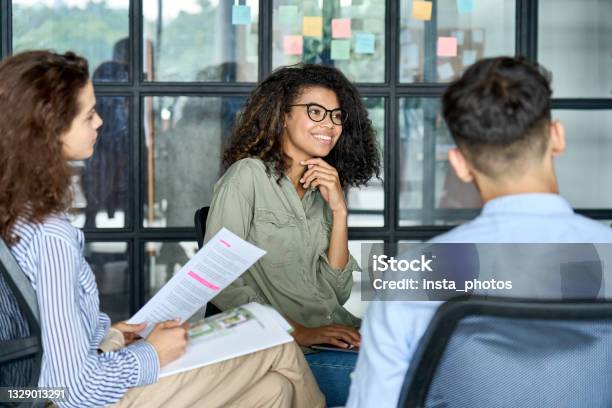 Diverse Smiling Happy Colleagues Listening To Mentor Leader In Modern Office Stock Photo - Download Image Now