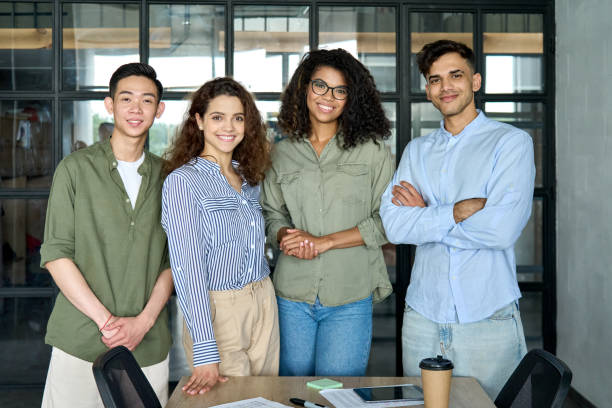 Young multiracial business people team standing in office. Group portrait Diverse multiracial happy smiling colleagues international business startup creative team students standing looking at camera in modern office. Ethnicity, diversity, cooperation concept. Portrait career girl stock pictures, royalty-free photos & images