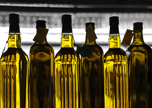 Olive Oil in different glass bottles in a row for sale on market.