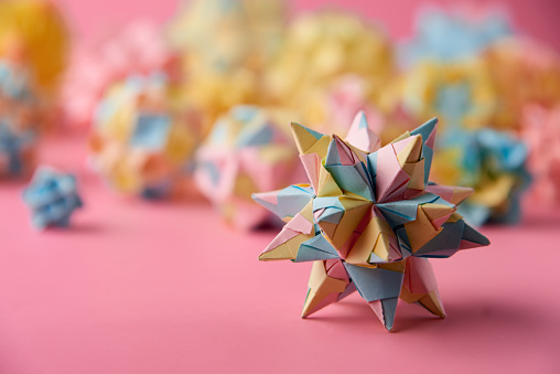 Set of multicolorÂ handmade modularÂ origami balls or Kusudama Isolated on pink background. Visual art, geometry, art of paper folding, paper crafts. Close up, selective focus, copy space.