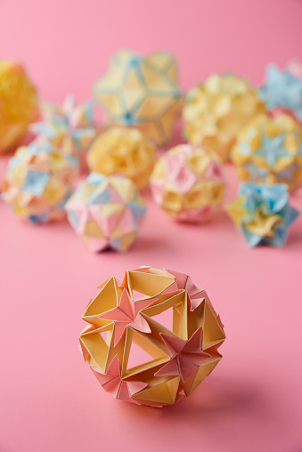 Set of multicolorÂ handmade modularÂ origami balls or Kusudama Isolated on pink background. Visual art, geometry, art of paper folding, paper crafts. Close up, selective focus, copy space.