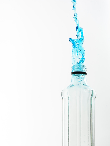 Octagon shaped glass bottle with water frozen with high speed flash photography. Giving a slow motion effect to the water