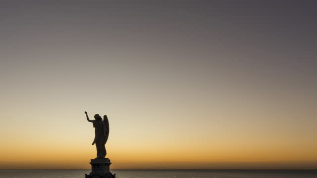 Night to Day Timelapse of an Angel Statue with Sunrise over the Ocean