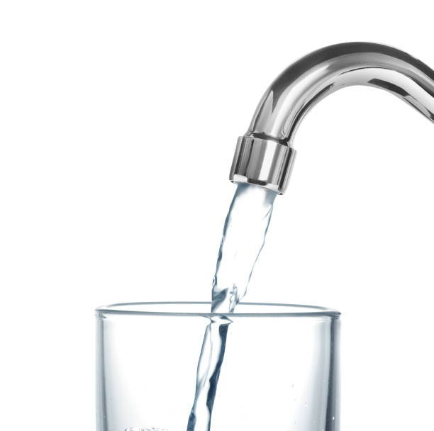 istock Filling glass with water from tap on white background 1329019828