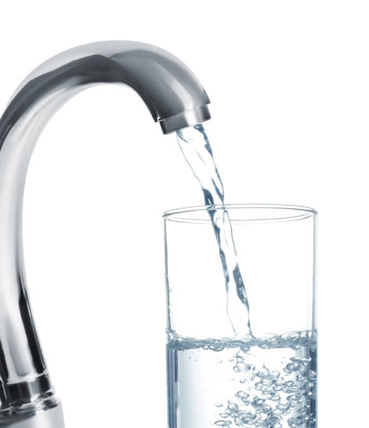 istock Filling glass with water from tap on white background 1329019831