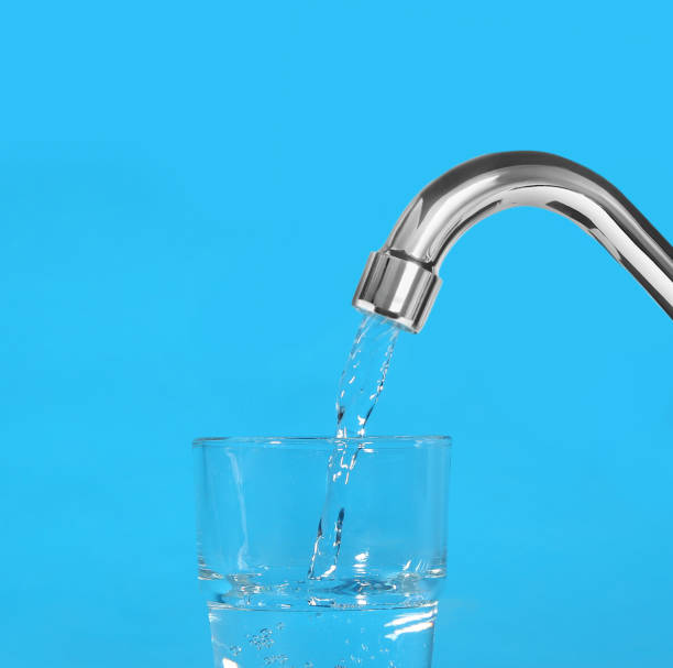 水色の背景にタップから水でガラスを充填 - water faucet running water glass ストックフォトと画像