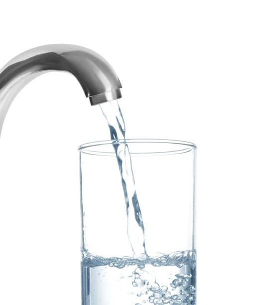 istock Filling glass with water from tap on white background 1329020482