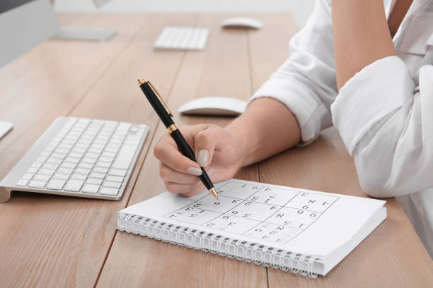 istock Woman solving sudoku puzzle at table, closeup 1329020611