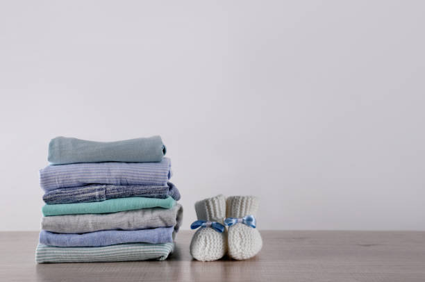 istock Stack of baby boy's clothes and booties on wooden table against white background, space for text 1329021281