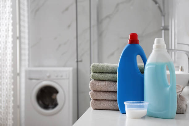 istock Stack of folded towels and detergents on white table in bathroom, space for text 1329021707