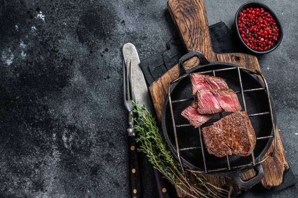 istock Grilled fillet mignon beef steak on a grill. Black background. Top view. Copy space 1329023997