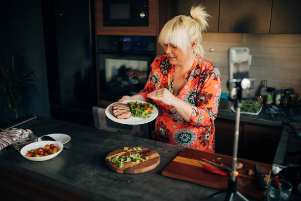 istock Female chef explaining which ingredient she used to make the sirloin steak with roasted vegetables, while filming her food vlog, from her modern kitchen 1329025954