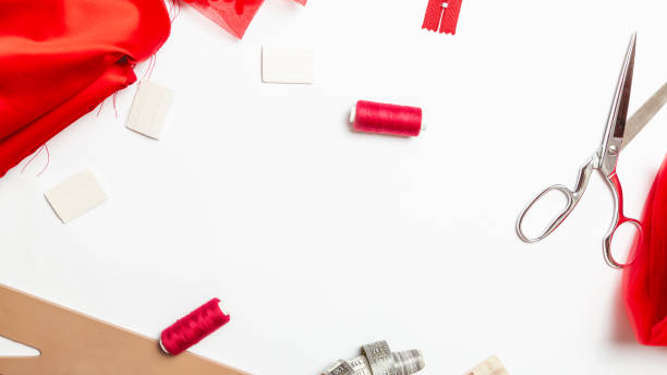 istock Tailor's work desk. Sewing accessories: thread and scissors, red fabric on white background 1329027149