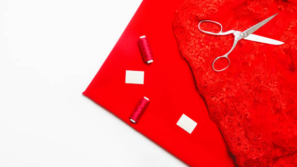 istock sewing hobby with tools, thread, scissors, red satin fabric white background top view. copy space 1329027151