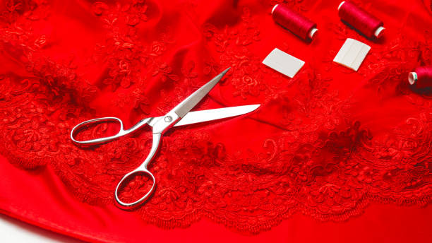 istock tailoring concept. elegant fabric white guipure on red satin with scissors and spool on white background 1329027178