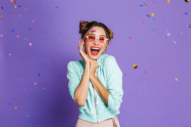Portrait of a cheery young girl Portrait of a cheery young girl with bright makeup over violet background, celebrating under confetti shower woman birthday cake stock pictures, royalty-free photos & images