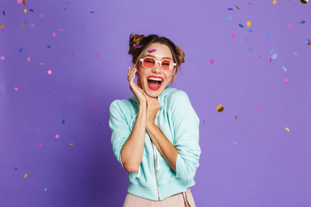 Portrait of a cheery young girl Portrait of a cheery young girl with bright makeup over violet background, celebrating under confetti shower cake models stock pictures, royalty-free photos & images