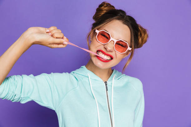 Portrait of a funny young girl with bright makeup Portrait of a funny young girl with bright makeup isolated over violet background, eating chewing gum chewing gum stock pictures, royalty-free photos & images