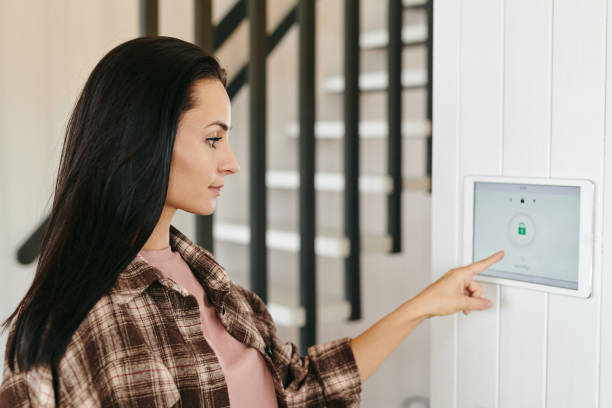 istock Young housewife pointing at tablet with security system 1329032191