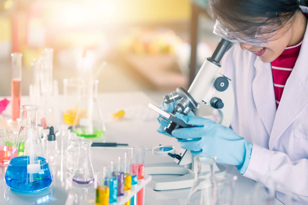 istock Young Asian medical technologist female making testing with test tube while doing research in science laboratory 1329032282