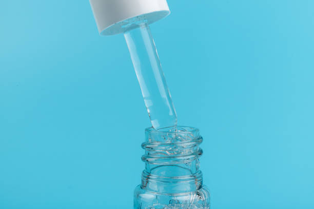 istock face serum drop with bottle on blue background. 1329033194