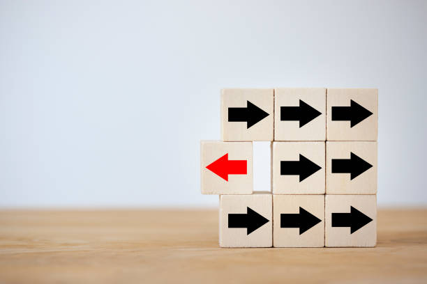 istock Wooden block with red arrow facing opposite direction black arrowd, different thinking, individiue and standing from the crowd. 1329033839