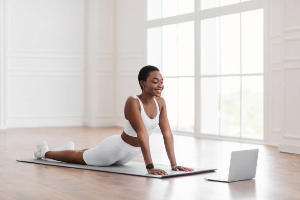 istock Young african woman stretching back on mat with pc 1329036588