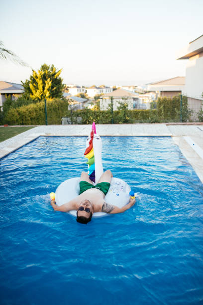 istock Man on unicorn float holding squirt gun in swimming pool 1329037157