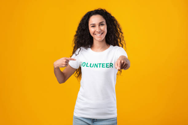 istock Joyful female volunteer activist pointing at camera posing in studio 1329037182