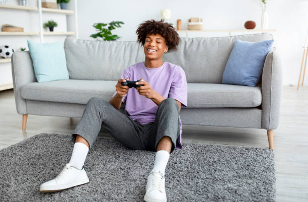 Having Fun at Home. Cheerful Black Teen Guy with Joystick Playing Online  Computer Games, Sitting on Couch Indoors Stock Image - Image of computer,  person: 227478857