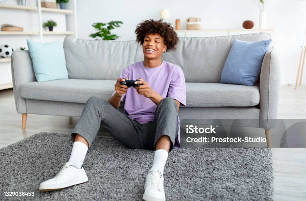 Happy Black Teenager Enjoying Videogame On Playstation Having Fun At Home Full Length Stock Photo - Download Image Now