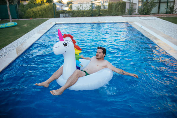 istock Man on unicorn float holding squirt gun in swimming pool 1329039435