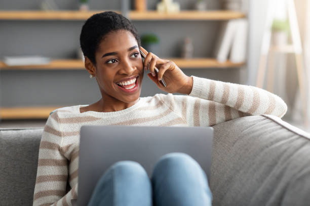 istock Home Office. Positive African Freelancer Lady Talking On Cellphone And Using Laptop 1329040040