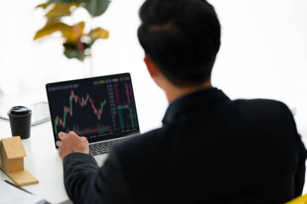 istock Young money businessman sitting staring at a computer screen displaying a cryptocurrency featuring stock tickers or graphs. Stock trading platform concept. professional financial advisor. 1329040995