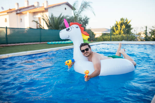 istock Man on unicorn float holding squirt gun in swimming pool 1329042072