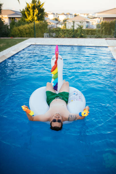 istock Man on unicorn float holding squirt gun in swimming pool 1329042931