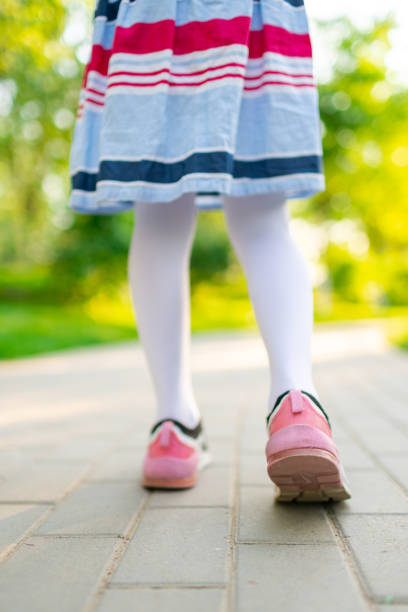 маленькая девочка идет по дороге крупным планом - healthy lifestyle nature sports shoe childhood стоковые фото и изображения