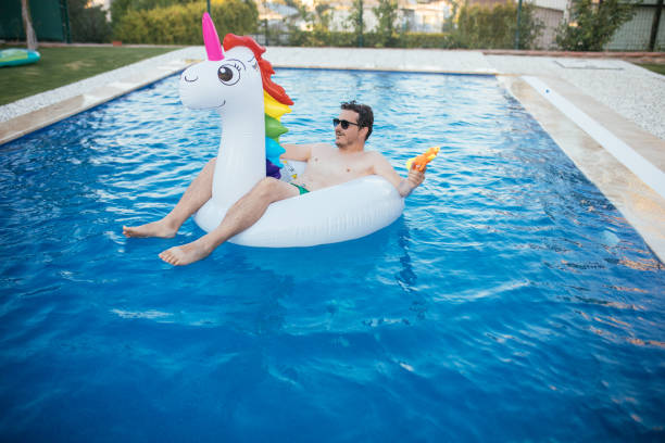istock Man on unicorn float holding squirt gun in swimming pool 1329045556