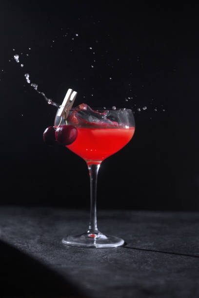 istock A glass with an alcoholic cocktail made by a bartender decorated with cherries on a clothespin and splashes 1329047065