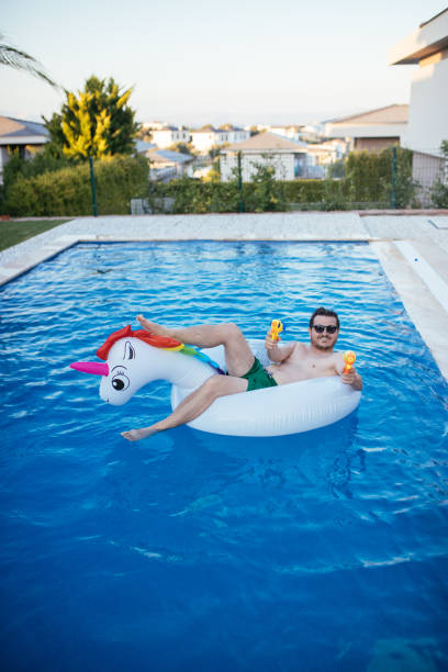 istock Man on unicorn float holding squirt gun in swimming pool 1329047639